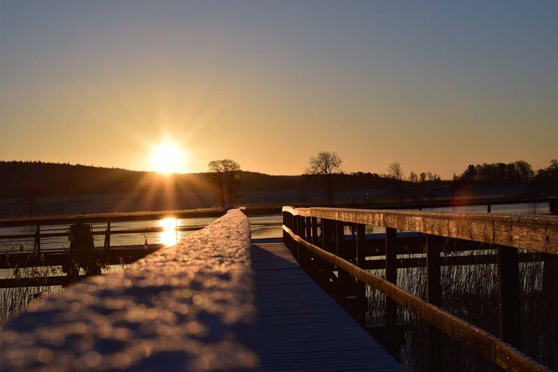 Solnedgång vid Vänerns strand i Vänersborg med brygga i förgrunden